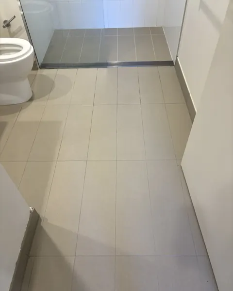 Grey stone bathroom floor after cleaning and sealing, clean grout lines, toilet in the corner